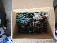 Box filled with tangled green-wire C9 string lights, various colored bulbs visible