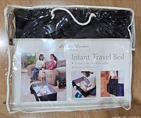 Front view of Eddie Bauer Infant Travel Bed in clear carry case showing product information card