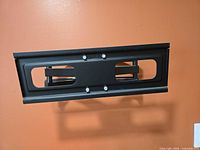 Front view of mount folded against wall showing mounting plate and hardware
