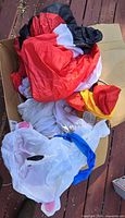 Box containing deflated red, white and other colored nylon inflatables