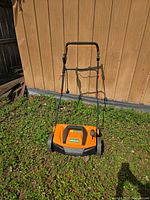 Front perspective of orange and black IronMax scarifier, handle raised