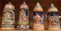 Four tall relief beer steins on upper shelf