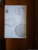 Front view of sealed Smart Light Starter Kit box showing Google Home Mini and GE bulb