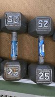 Two 25 lb hex dumbbells showing weight markings and rust on one