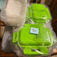 Stack of off-white bases and multiple green vented lids in plastic wrap