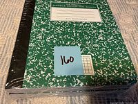 Shrink-wrapped green marble composition notebook with blue lot sticker
