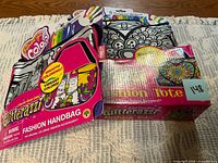 Both Glitterazzi kits, showing handbag kit on left and tote kit on right in retail packaging