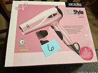 Front of sealed box showing Andis Pink Style 1875 W hair dryer and included attachments