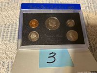 Front of sealed 1983 proof set showing five coins in holder and blue cover