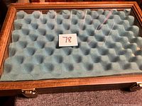 Top view of wooden display case showing glass lid, blue foam interior