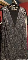 Front view of black sleeveless sequin dress on hanger