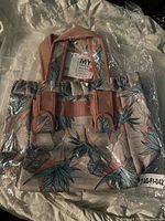 Front view of MyTagAlongs lunch bag in packaging showing leaf pattern and handles