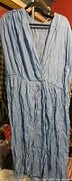 Full view of blue sleeveless crinkled maxi swim cover-up on hanger