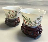 Two porcelain bowls on carved wooden stands front view