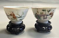 Front view of both bowls on stands showing painted scenes