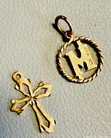 Front view of both pendants: cross and rope-edge "M"