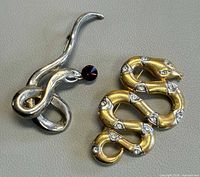 Both snake brooches side by side showing overall design and finishes