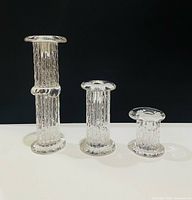 Front view of three graduated Kosta Boda candlesticks