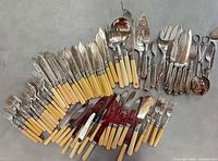 Assorted silver-plated cutlery with cream handles and serving utensils