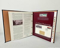 Open binder displaying interior pages with mounted first-day cover and stamps