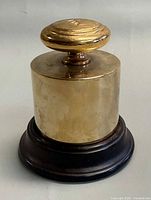 Full view assembled brass weight lighter on wood base