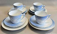 Four cups each on a saucer with dessert plates beneath, showing pattern and quantity