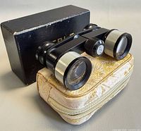 Opera glasses resting on brocade case with box behind