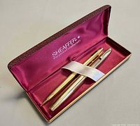 Open Sheaffer presentation box showing fountain pen and pencil secured by elastic strap