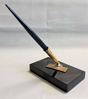 Pen inserted in brass holder on black stone base