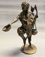 Front view of bronze water carrier sculpture showing bowl, staff and hanging vessel