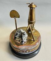 Full view showing brass lamp, shovel tool, coal piece on stone base