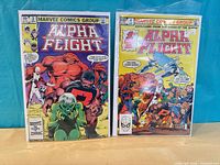 Front covers of Alpha Flight issues #1 and #2 in bags with boards