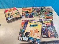 Three stacks of various Charlton comics on table showing covers of Fightin' Marines, Fightin' 5, Ghostly Tales, Attack and others