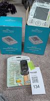 Two Easy@Home blood pressure monitors in boxes beside sealed ADC pulse oximeter