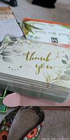 Stack of thank-you cards with gold script in botanical design