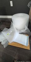 Bubble wrap roll, loose sheets and stack of mailers on floor
