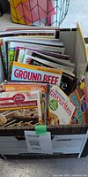 Box containing stack of assorted cooking magazines and booklets