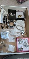 Overhead view of assorted costume jewellery pieces including bracelets, earrings, rings and brooch inside box