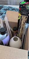 Box containing diffuser supplies including Aura reed set, Pier 1 oil, ceramic vase, loose reeds, small oil bottle
