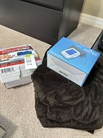 Boxed DR-HO'S TENS device, boxed blood pressure monitor, folded dark brown recliner cover