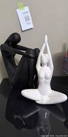 White and black female nude figurines together on display surface