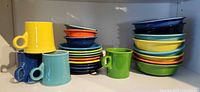 Stacked Fiesta mugs, bowls and plates on shelf