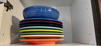 Stack of eight plates and one bowl showing color variety and sizes