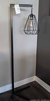 Full view of black metal floor lamp standing on square base