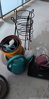 Full lot view: metal plant stand, stacked pots, watering cans, attachments