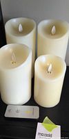 Four ivory flameless candles and remote displayed