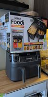 Air fryer unit with box displayed on top