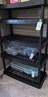 Full view of five-shelf black plastic shelving unit with some bins shown for scale (bins not included)