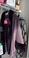 Purple ombré faux fur shawl and grey plaid hooded shawl hanging on rack