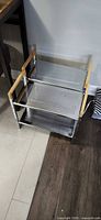 Two metal shoe racks, chrome frames, perforated shelves, wood handles